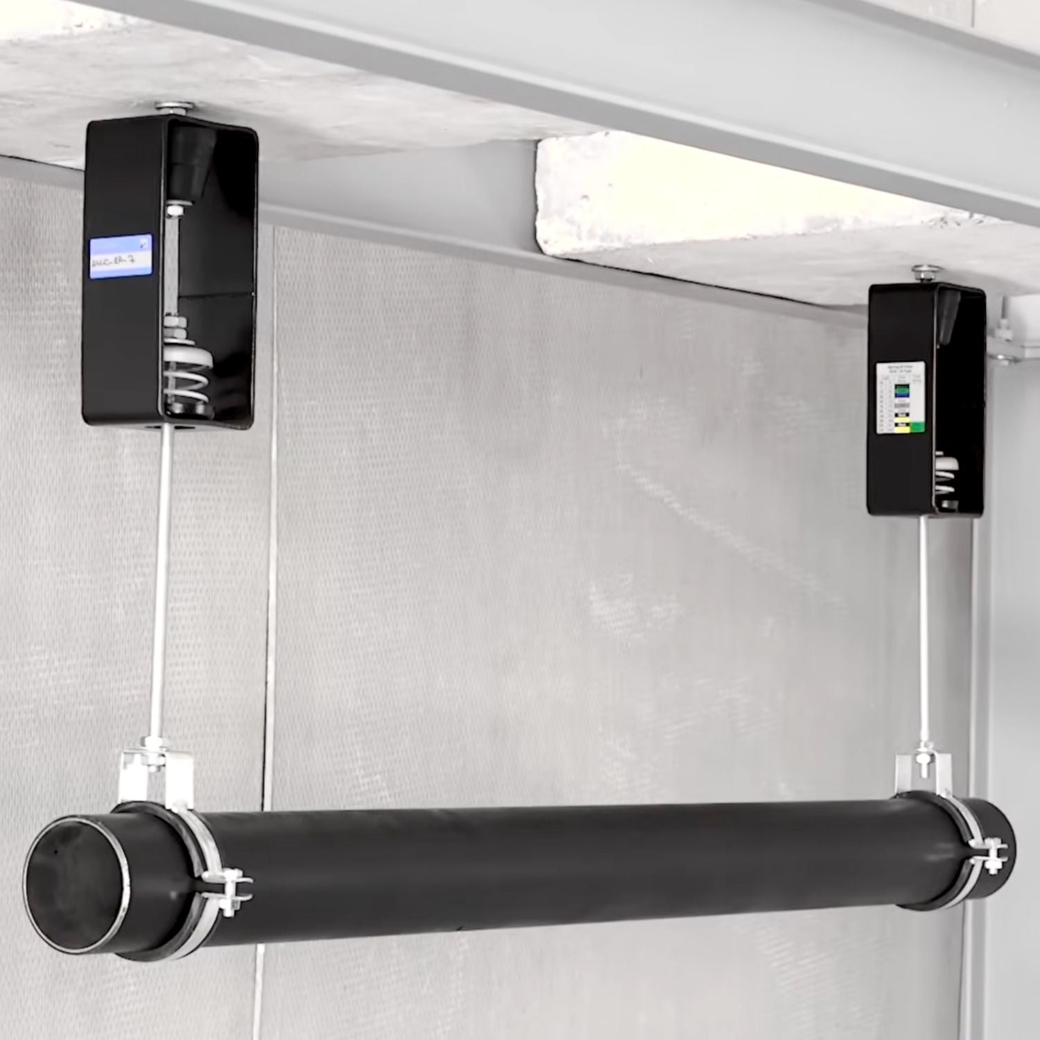 Acrefine acoustic spring and rubber combined hangers suspended from concrete ceiling supporting a pipeline.