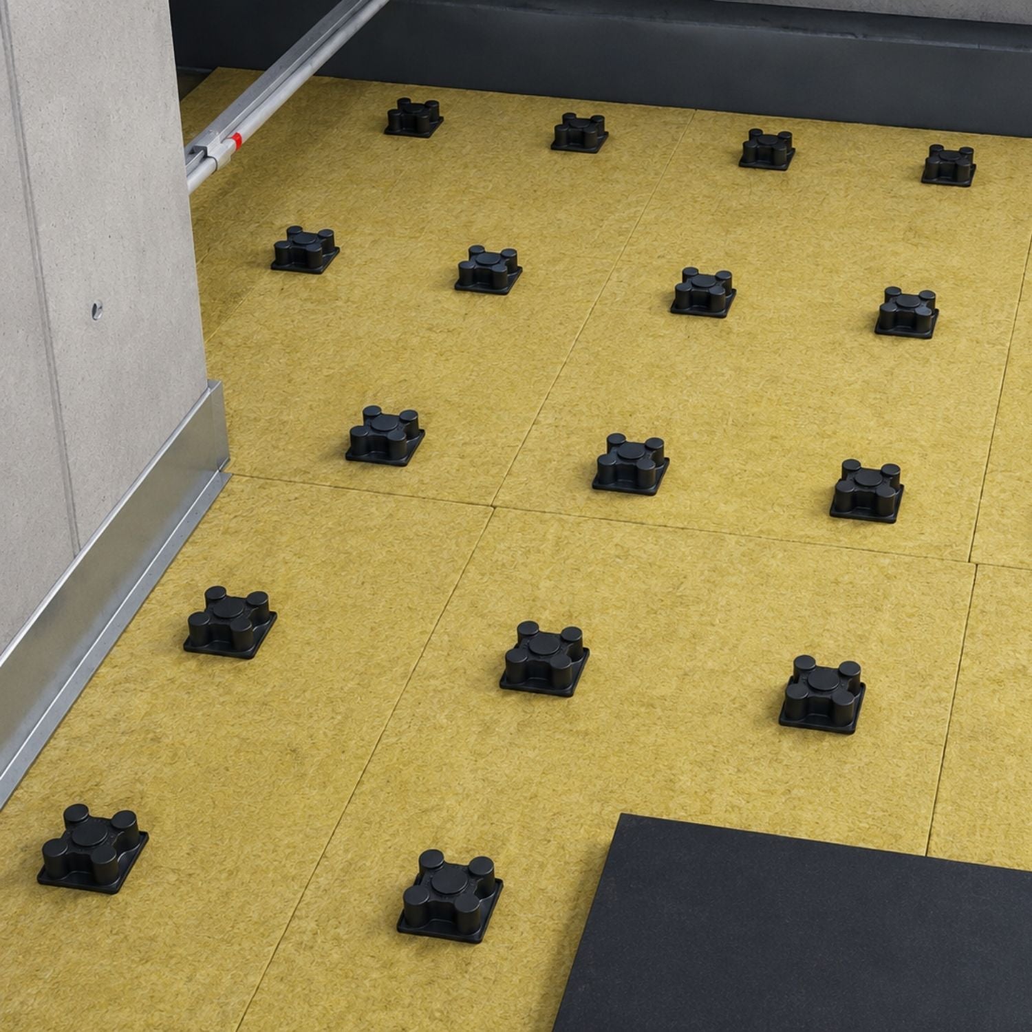 Symmetrical grid layout of Acrefine floating floor mounts placed over acoustic mineral wool insulation boards.