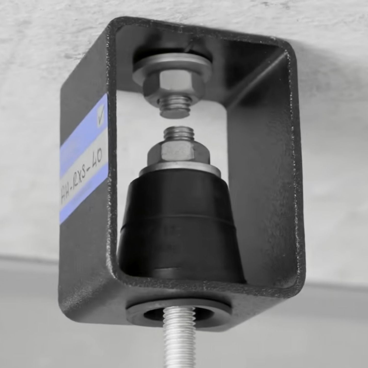Close-up view of Acrefine housed elastomer vibration hanger showing the internal rubber element and leveling nut under the ceiling.