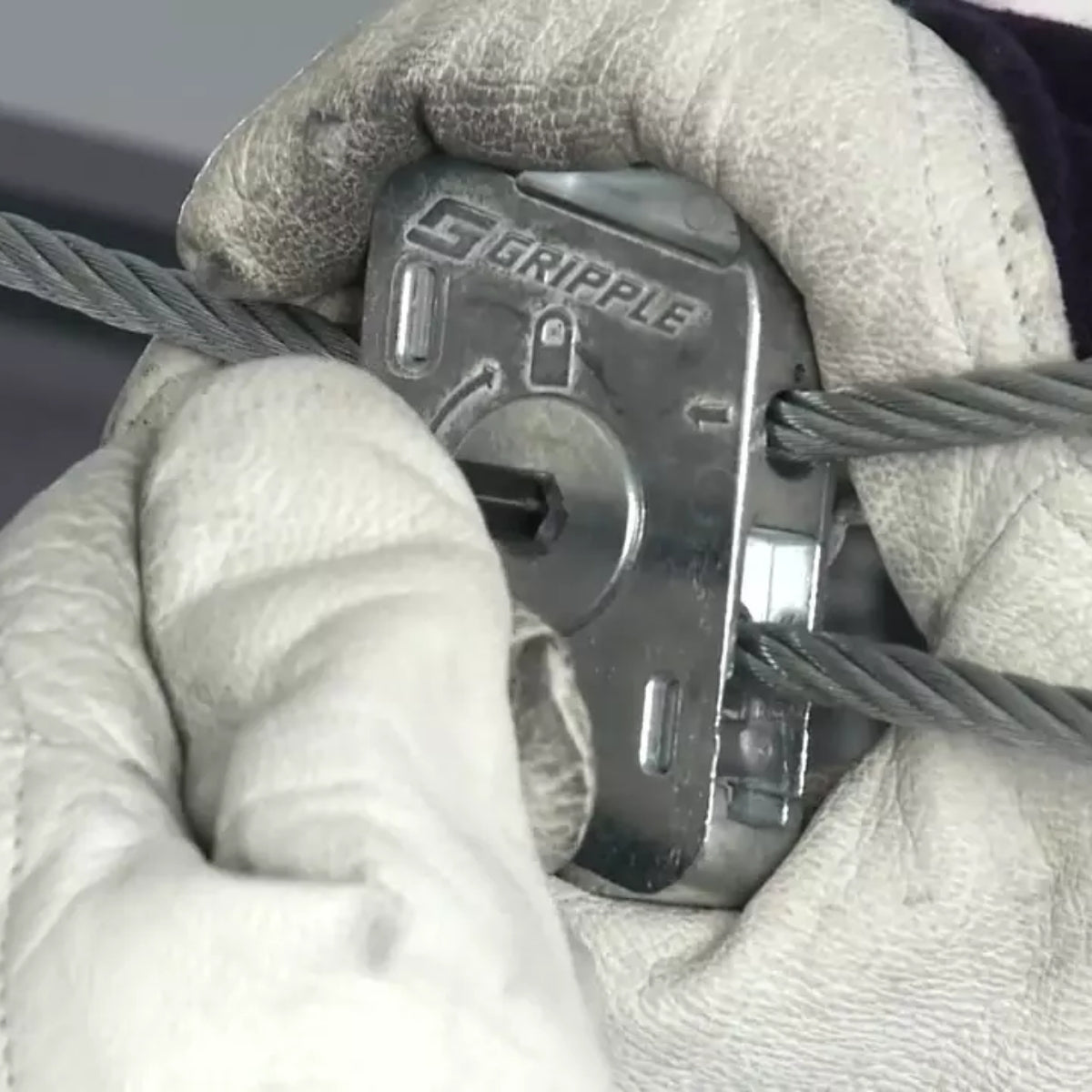 Close-up of gloved hands threading wire rope through a Gripple Dynamic.