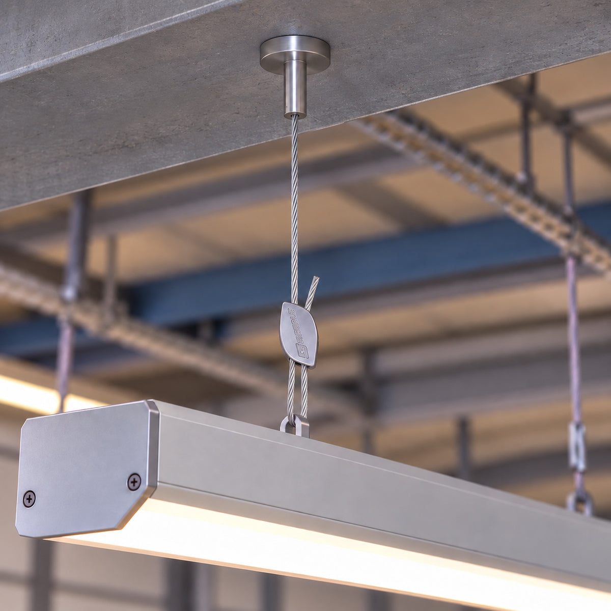 A linear LED fitting suspended from a magnetic pad hanger below a concrete soffit.