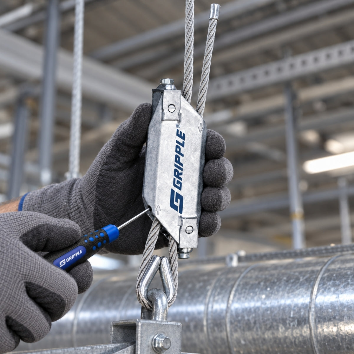 The Setting Key pushed into the side port of a Gripple Lockable to release the wire rope on a duct hanger.