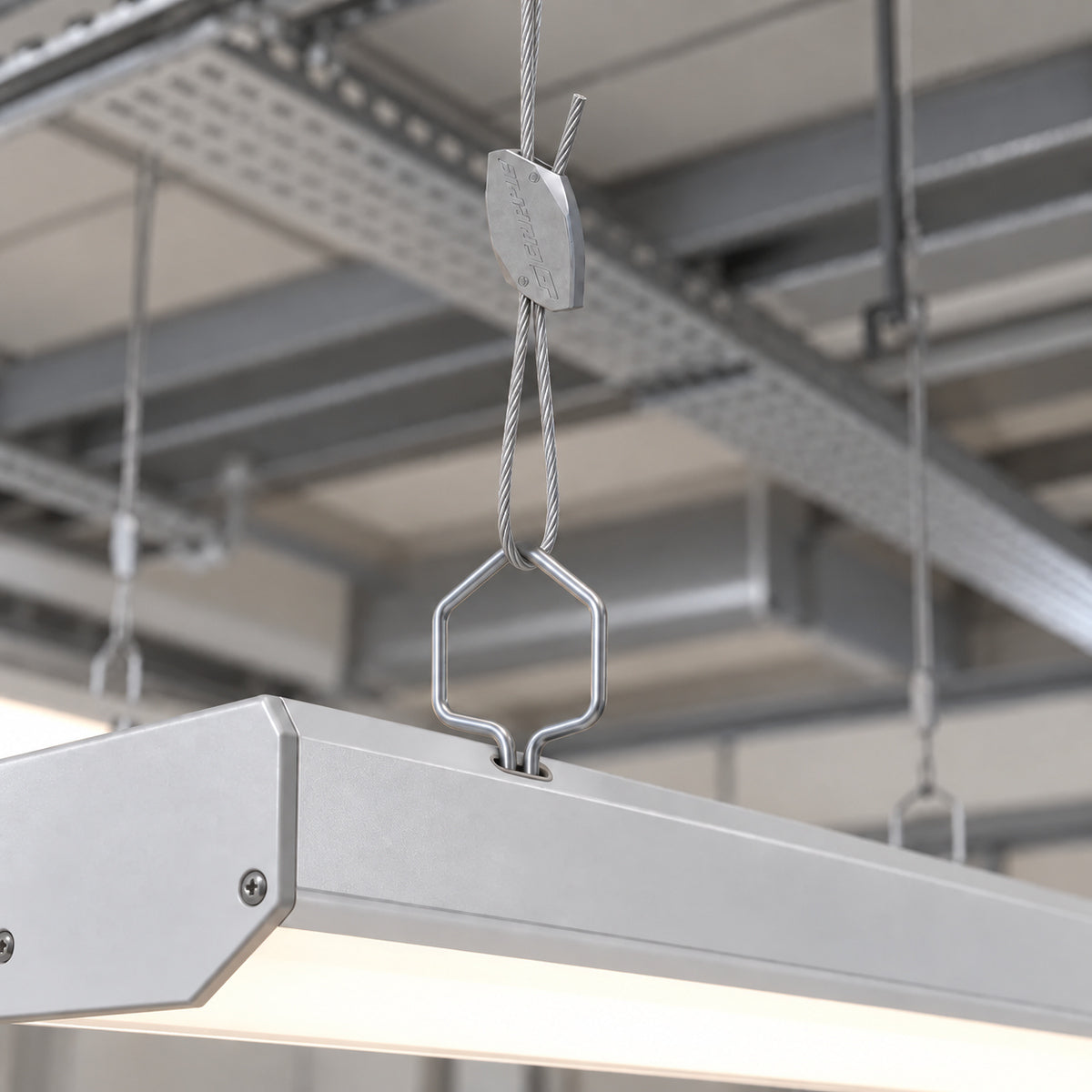 A linear light fitting suspended on spring clips below a services ceiling.