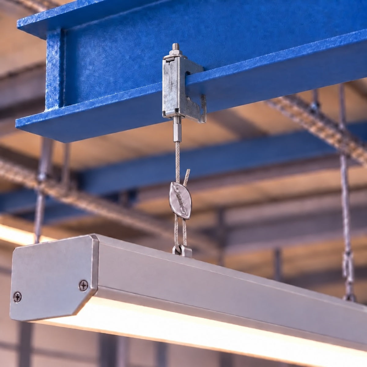 A Tiger Clip fixed to a blue steel beam with a light fitting hung below.